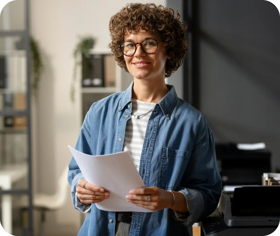 Une collaboratrice souriante tenant des documents